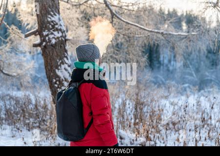 Ein Mann im Winter atmet draußen eine Wolke aus Dampf und Rauch aus Stockfoto