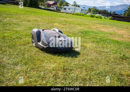 LOM, Norwegen, 25. Juni 2023: Nahaufnahme eines Mähroboters, der mit Strom betrieben wird, schneidet Gras autonom in der Nähe des Lom Stave Churc Stockfoto
