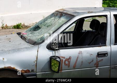 Ein altes Auto mit kaputter Windschutzscheibe und Spuren von Vandalismus an der Karosserie, ein kaputter Rückspiegel Stockfoto