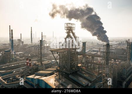 Dieses Bild zeigt eine große Industriefabrik mit weißem Rauch, der aus hohen Rohren weht Stockfoto