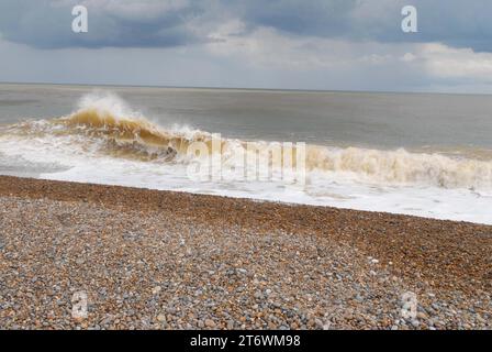 Eine große, kräftige Welle bricht am Morgen nach dem Sturm Poly auf Shingle Beach mit Seespray auf der Nordseeküste auf. Stockfoto