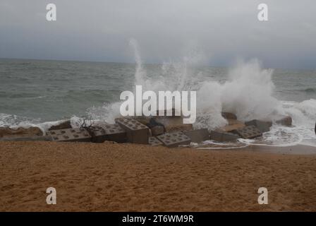 White Sea Spray schießt von großen Wellen auf die Panzerblockflut-Verteidigungsanlagen, die zum Schutz der Zugangsrampe von Hemsby Independent Lifeboat Crew eingesetzt werden. Stockfoto