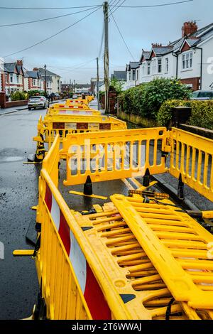 Rohrverlegung in Cardiff. Hellgelbe Sicherheitsbarrieren schützen den Arbeitsbereich. Überlastete Straße. Utility funktioniert. Vorortstraße. Stockfoto