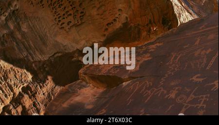 Petroglyphen unter einem natürlichen Baldachin aus alten und außerirdischen Sandsteinformationen am Atlatl Rock im Valley of Fire von Nevada. Stockfoto