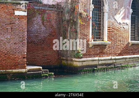 Die Textur einer alten Ziegelmauer. Alte rote Ziegelsteinmauer mit an einem sonnigen Tag. Tonziegelwände Italiens. Stockfoto