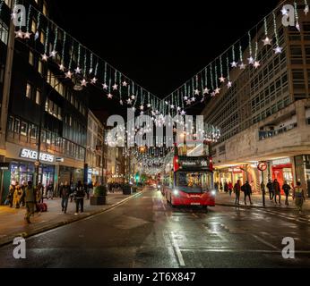 London, UK - 8. November 2023: Oxford Street, eine berühmte Einkaufsstraße im Zentrum Londons mit Weihnachtslichtern und rotem Londoner Bus. Stockfoto