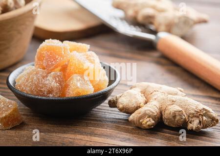 Kandierte Ingwerstücke und Ingwerwurzeln auf hölzernem Küchentisch. Gesunde Süßigkeiten. Stockfoto