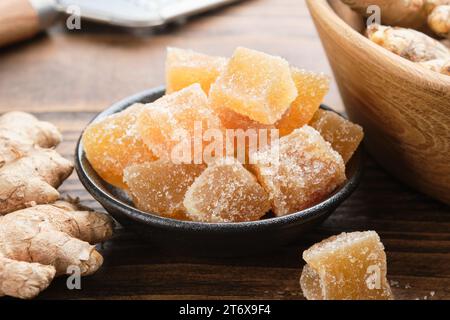 Schüssel mit kandierten Ingwerstücken in der Nähe und Ingwerwurzeln auf dem Tisch. Gesunde Süßigkeiten. Stockfoto