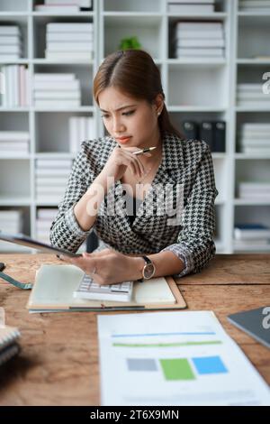 Die weibliche Mitarbeiterin hält einen Stift und prüft die Finanzunterlagen für Investitionen. Stockfoto