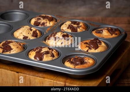 Hausgemachte Bananen- und Schokoladenmuffins aus dem Ofen in einem Blech mit schmelzender Schokolade. Stockfoto