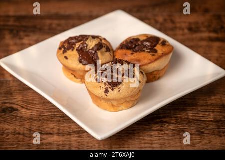 Hausgemachte Bananen- und Schokoladenmuffins aus dem Ofen auf einem weißen Teller mit schmelzender Schokolade. Stockfoto
