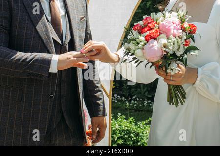 Die Braut legt dem Bräutigam den Ehering an die Hand. Nahaufnahme Stockfoto
