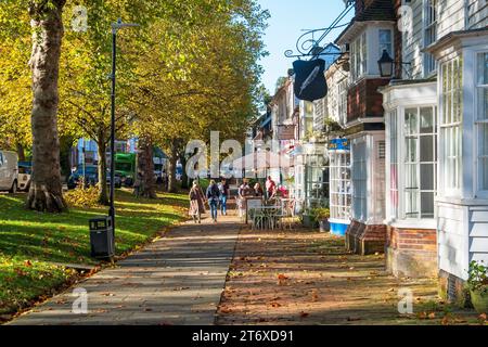 Tenterden High Street, von Bäumen gesäumte Straße, breiter Bürgersteig mit Geschäften und Cafés, an einem sonnigen Herbsttag, Kent, Großbritannien Stockfoto