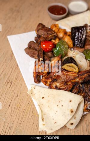 Blick von oben auf verschiedene Kebabs mit Sauce auf einem weißen Teller in einem Restaurant. Stockfoto
