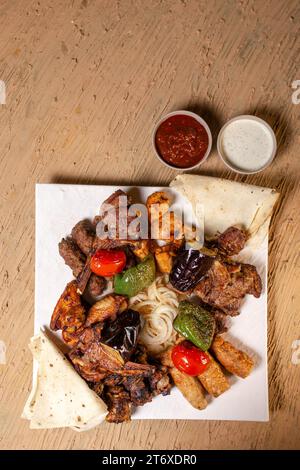 Blick von oben auf verschiedene Kebabs mit Sauce auf einem weißen Teller in einem Restaurant. Stockfoto