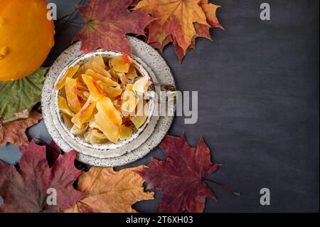 Kandierter und getrockneter Kürbis. Nahaufnahme von kandierten Früchten von hausgemachtem Kürbis aus einer natürlichen Farm, bestreut mit Puderzucker in handgemachtem Steingut. Stockfoto