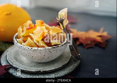 Kandierter und getrockneter Kürbis. Nahaufnahme von kandierten Früchten von hausgemachtem Kürbis aus einer natürlichen Farm, bestreut mit Puderzucker in handgemachtem Steingut. Stockfoto