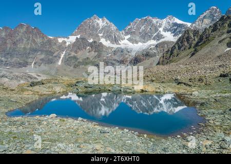 Die Gipfel der italienischen Alpen in der Bernina-Gruppe spiegeln sich in einem kleinen Alpensee. Berglandschaft mit Teich, Wasserreflexionen und Gletschern. Stockfoto