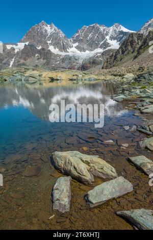 Die Gipfel der italienischen Alpen in der Bernina-Gruppe spiegeln sich in einem kleinen Alpensee. Berglandschaft mit Teich, Wasserreflexionen und Gletschern. Stockfoto