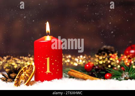Bayern, Deutschland - 10. November 2023: Rote Kerze brennt für den 1. Adventsabend mit festlichen Weihnachtsdekorationen. Erster Adventsgruß FOTOMONTAGE *** Rote Kerze brennt zum 1. Adventsverziert mit festlicher Weihnachtsdekoration. Erster Adventsgruß FOTOMONTAGE Stockfoto