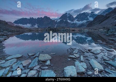 Alpiner Sonnenaufgang mit Morgenhimmel, der sich in einem perfekt noch kleinen See spiegelt. Der Forbici-See in der Nähe des Piz Bernina in den italienischen Alpen. Stockfoto