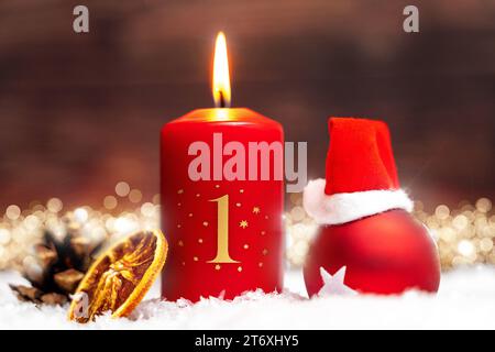 Bayern, Deutschland - 10. November 2023: Rote Kerze brennt für den 1. Adventsabend mit festlichen Weihnachtsdekorationen. Erster Adventsgruß FOTOMONTAGE *** Rote Kerze brennt zum 1. Adventsverziert mit festlicher Weihnachtsdekoration. Erster Adventsgruß FOTOMONTAGE Stockfoto