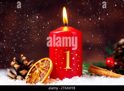 Bayern, Deutschland - 10. November 2023: Rote Kerze brennt für den 1. Adventsabend mit festlichen Weihnachtsdekorationen. Erster Adventsgruß FOTOMONTAGE *** Rote Kerze brennt zum 1. Adventsverziert mit festlicher Weihnachtsdekoration. Erster Adventsgruß FOTOMONTAGE Stockfoto