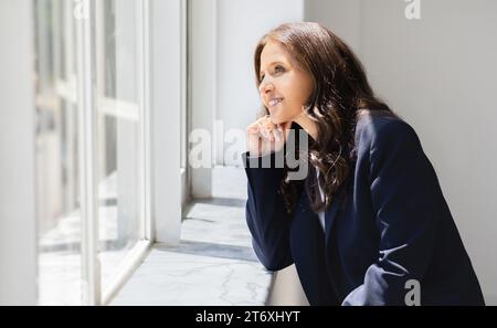Seitenansicht einer reiferen Mitarbeiterin mit Blick durch das Fenster Stockfoto