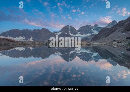 Alpiner Sonnenaufgang mit Morgenhimmel, der sich in einem perfekt noch kleinen See spiegelt. Der Forbici-See in der Nähe des Piz Bernina in den italienischen Alpen. Stockfoto