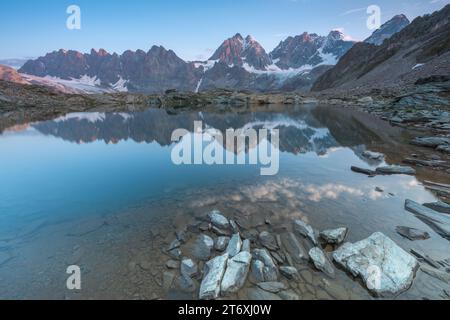 Alpiner Sonnenaufgang mit Morgenhimmel, der sich in einem perfekt noch kleinen See spiegelt. Der Forbici-See in der Nähe des Piz Bernina in den italienischen Alpen. Stockfoto