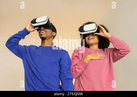 Schwarzes Paar im virtuellen Reich, das Videospiele mit Headsets in Innenräumen spielt Stockfoto
