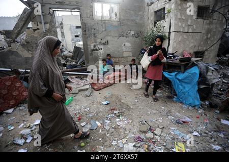 Rafah, Gaza. November 2023. Amal al-Robayaa 44, (L) gehen, während ihre Söhne in den Ruinen des Familienhauses sitzen, das bei einem israelischen Streik in Rafah im südlichen Gazastreifen am Sonntag, den 7. November 2023 zerstört wurde. Robayaa sagt, dass der Wohnblock, in dem er lebte, am 7. Oktober, dem ersten Tag des Krieges in Gaza, durch einen israelischen Bombardement zerstört wurde. Amal Rabayaa, Ehemann von Imad, versickert nun mit anderen Familienmitgliedern in einer UN-Schule in Rafah, kehrt aber am Morgen in ihr Zuhause zurück und stellt sich dem täglichen Kampf um Nahrung und Wasser. Foto: Ismael Mohamad/UPI Credit: UPI/Alamy Live News Stockfoto