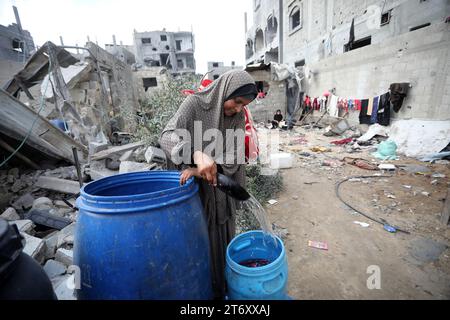 Rafah, Gaza. November 2023. Amal al-Robayaa 44, (R), bringt Wasser zwischen den Ruinen des Familienhauses, das bei einem israelischen Streik in Rafah im südlichen Gazastreifen am Sonntag, den 7. November 2023 zerstört wurde. Robayaa sagt, dass der Wohnblock, in dem er lebte, am 7. Oktober, dem ersten Tag des Krieges in Gaza, durch einen israelischen Bombardement zerstört wurde. Amal Rabayaa, Ehemann von Imad, versickert nun mit anderen Familienmitgliedern in einer UN-Schule in Rafah, kehrt aber am Morgen in ihr Zuhause zurück und stellt sich dem täglichen Kampf um Nahrung und Wasser. Foto: Ismael Mohamad/UPI Credit: UPI/Alamy Live News Stockfoto