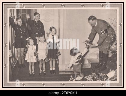 Adolf Hitler mit Kindern 1939 Führer von Nazi-Deutschland erhält Blumen von einem Säugling, während kleine Kinder mit BDM-Mädchen und Hitler-Jugend in Uniform den Heil-Hitler-Gruß geben. Stockfoto