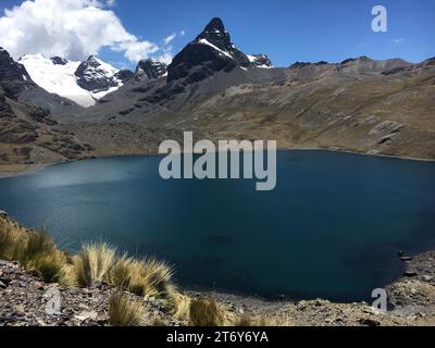 Ein idyllischer Alpensee im Herzen einer Bergkette, umgeben von üppigem Laub und majestätischen Gipfeln Stockfoto