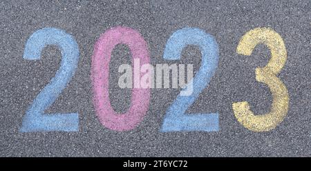 Starten Sie das neue Jahr 2023 in Straßenfarbe auf dem Asphalt, starten Sie das Trip-Konzept. Feierliche Reise ins neue Jahr Stockfoto