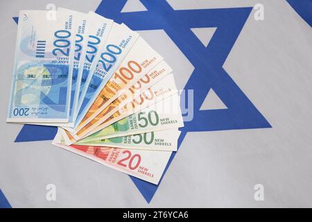 Neue israelische Schekel-Banknoten mit verschiedenen Nominalen. Fan von NIS Neuer Schekel, der auf die israelische Nationalflagge legt Stockfoto