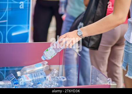 Frau, die Plastikflaschen in den Mülleimer wirft. Nahaufnahme: Moskau, Russland, 5. September 2023 Stockfoto