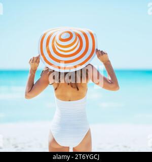 Junge Frau im Hut stehen am Strand. Rückansicht Stockfoto