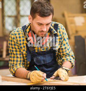 Nahaufnahme des Zimmermanns, der lange Holzplanke mit Lineal misst Stockfoto