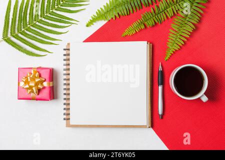 Tasse schwarzer Teestift Notizblock Geschenkbox angeordnete Reihe rot weiße Oberfläche Stockfoto