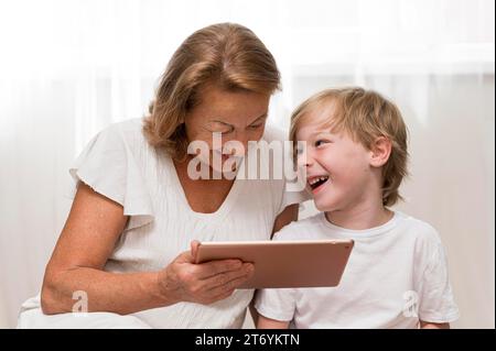 Glückliches Kind, Oma mit Tablet Stockfoto