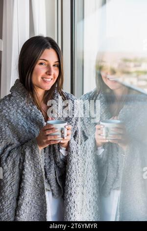 Reflektierendes lächelndes Porträt Frau, die Kaffeetasse Hand hält Stockfoto