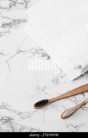 Hölzerne Zahnbürste, weiße Handtücher, Marmoroberfläche Stockfoto