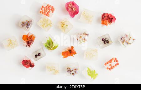 Eiswürfel mit hellen Blumen, weißem Hintergrund Stockfoto