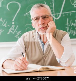 Konzentrierter alter Mathelehrer-Think-Schreibtisch Stockfoto