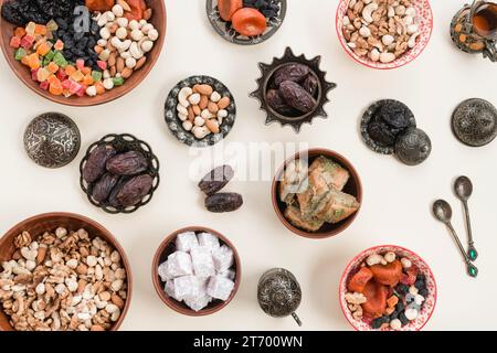 Erhöhter Blick auf getrocknete Früchte, Nüsse, Lukum, Baklava, Schüsseln, weiße Kulisse Stockfoto