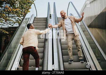 Zwei Freunde trafen sich an der Rolltreppe. Sie grüßen einander, indem sie die Hände schütteln. Stockfoto