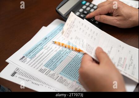 Ein Mann, der die Einkommensteuererklärung 1040 und die Quittungen organisiert. Unscharfer Hintergrund. Steuerzeit.Steuerkonzept. Nahaufnahme. Stockfoto