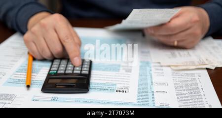 Ein Mann, der die Einkommensteuererklärung 1040 und die Quittungen organisiert. Unscharfer Hintergrund. Steuerzeit.Steuerkonzept. Nahaufnahme. Stockfoto